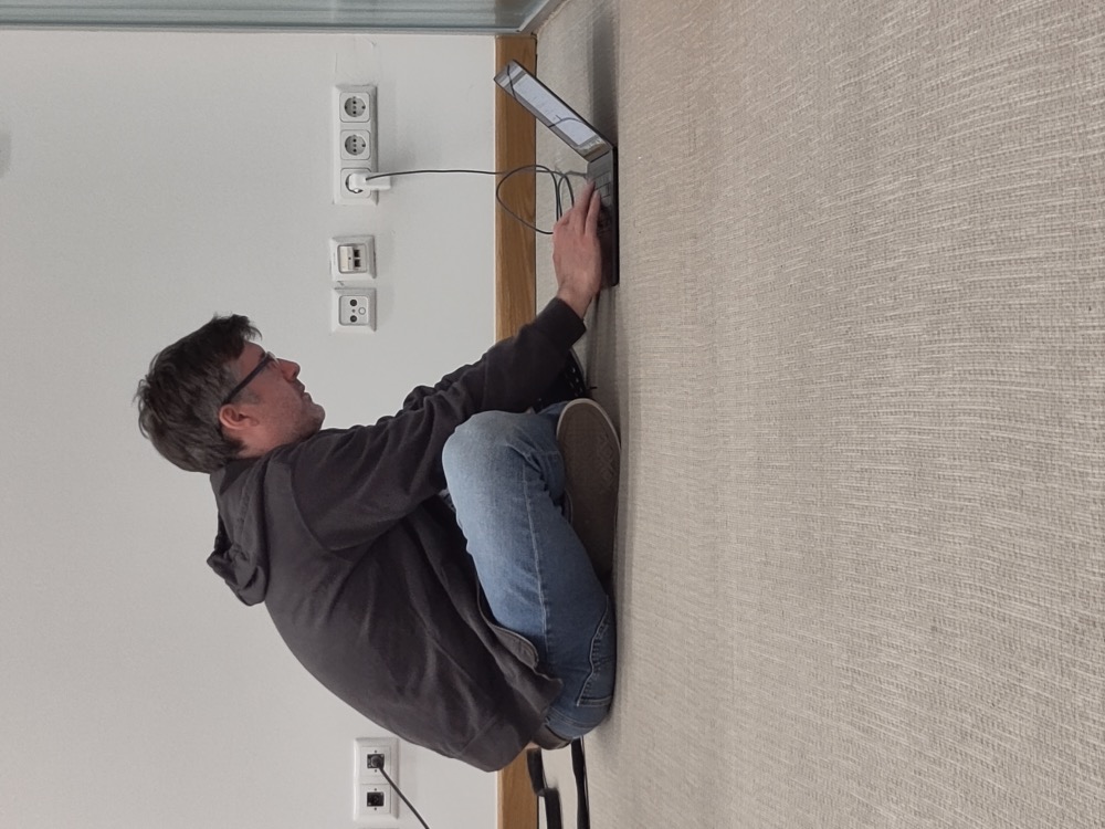 Ingo sitting on the floor at the EcoCor hackathon, working with multiple Claude Code agents on a laptop